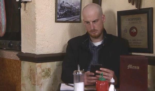 A bald man sits on his phone in the café in Coro<em></em>nation Street