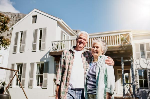 Shot of a happy senior couple standing together in front of their house.