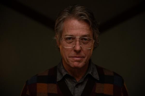 Hugh Grant looks into the camera through his glasses with a small smile as Mr Reed in the film Heretic