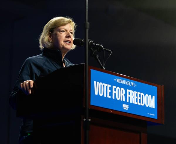 U.S. Senator Tammy Baldwin standing at a podium making opening remarks at a rally for Vice President Kamala Harris and Governor Tim Walz