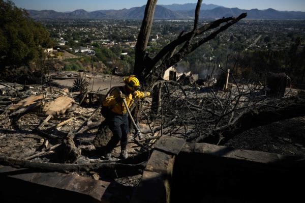 A Los Angeles Fire Department firefighter uses a hose line while extinguishing hot spots in the aftermath of a neighborhood of homes destroyed by wind driven wildfire on West Highland Drive. — AFP