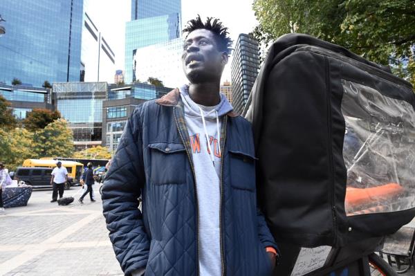 Mactor Sarr standing next to his pedicab in Columbus Circle