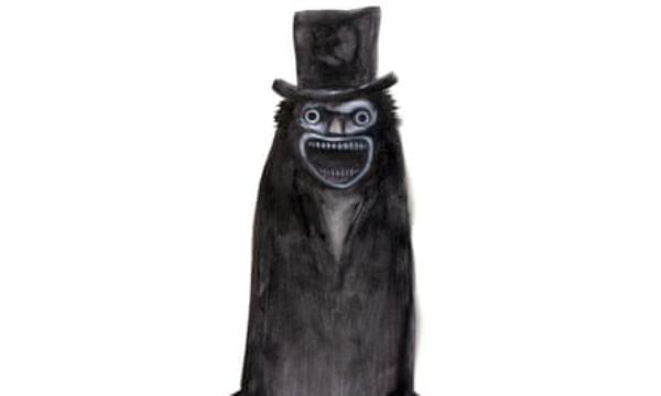 The Bababook creature, all in black, wearing a top hat. The creature’s eyes are wide and its mouth is open, showing its teeth