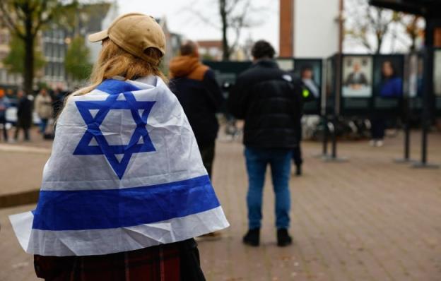 A woman wrapped in an Israel flag stands outside the place wher<em></em>e mayor of Amsterdam Femke Halsema attends a press co<em></em>nference following the violence targeting fans of an Israeli soccer team, in Amsterdam, Netherlands, November 8, 2024. 